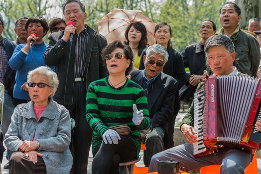 Shanghai, China - April 7, 2013: people singing revolutionary songs in fuxing park at the city of Shanghai in China on april 7th, 2013