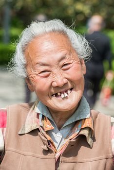 Shanghai, China - April 7, 2013: old chinese woman friendly toothless toothy smiling outddors portrait at the city of Shanghai in China on april 7th, 2013