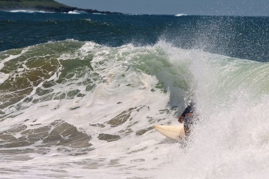 Surfer on surfboard riding inside wave tunnel