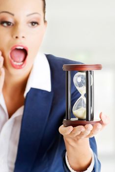 Young shocked business woman with hourglass - time concept