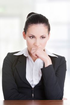 Sad business woman sitting behind the desk, isolated on white