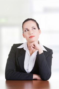 Pretty business woman in sitting at the desk and thinking, isolated on white