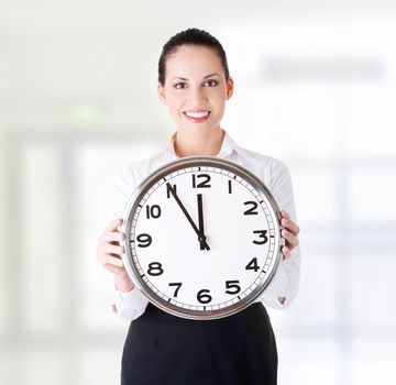 Happy young business woman holding office clock, isolated on white background