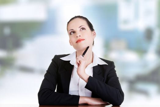 Pretty business woman in sitting at the desk and thinking, isolated on white