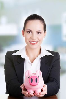 Happy business woman with her savings at the desk, isolated