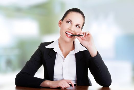 Pretty business woman in sitting at the desk and thinking, isolated on white