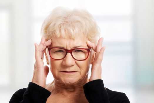 An old woman is eye glasses is having a headache. Isolated on white.