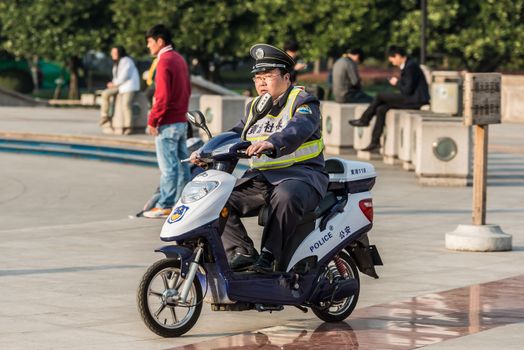Shanghai, China - April 7, 2013: policeman patrolling with electric motorcycle on people's square at the city of Shanghai in China on april 7th, 2013