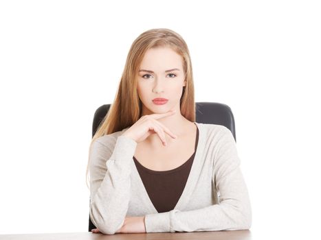 Beautiful casual woman sitting by a desk. Isolated on white.