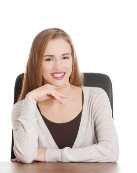 Beautiful casual smiling woman student sitting by a desk. Isolated on white.