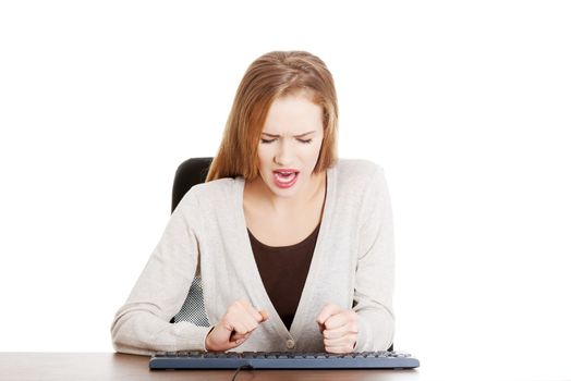 Beautiful casual woman writing on keyboard with anger.Isolated on white.