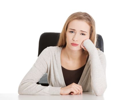 Sad, worried beautiful woman sitting by a desk. Isolated on white.