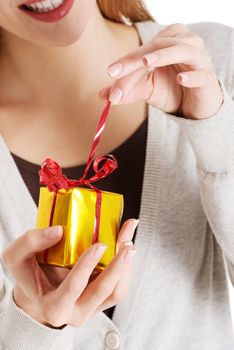 Beautiful woman unwrapping small present held in her hands.