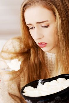 Young depressed woman is eating big bowl of ice creams to comfort herself. Depression, bulimia and diet concept.