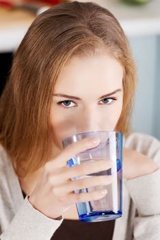 Beautiful woman drinking fresh water form a glass.