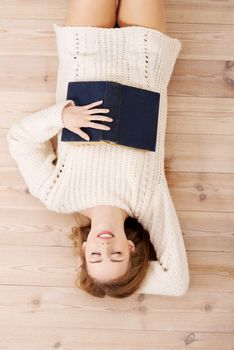 Relaxed young student woman lying on the floor and surrounded by books.