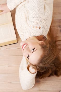 Relaxed young student woman lying on the floor and surrounded by books.