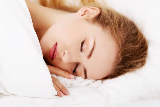 Sleeping woman lying in bed over white.