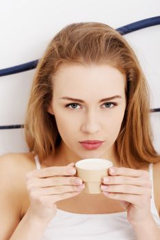 Beautiful caucasian woman in white lingerie is drinking small coffee, espresso.