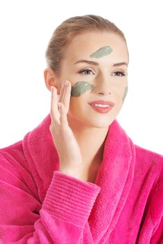 Beautiful caucasian woman in pink bathrobe is having facial mask. Spa concept. Isolated on white.