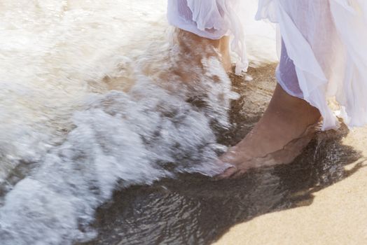 Pictore of feet on a beach and water. Over outdoor background and splashing water.