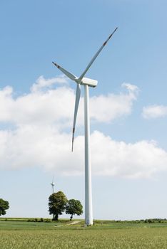 Windmill power generation over sunny landscape in a field.