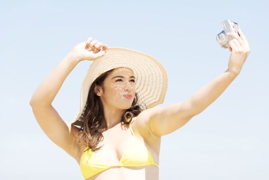 Beautiful young woman in a hat and swimsuit over seaside sunny day background.