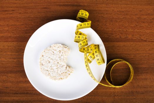One waffle rice on a plate and measuring tape. Over wooden background.