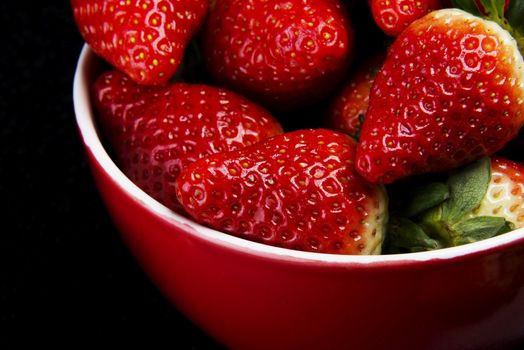 Fresh red strawberries in a bowl. Over black background.