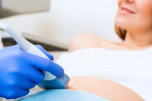 close-up of hands and abdominal ultrasound scanner for pregnant women