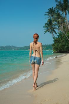 Beautiful girl walking on the tropical beach with palm trees 
