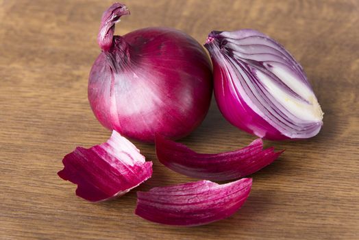 Red raw onion sliced into two. over wooden background.