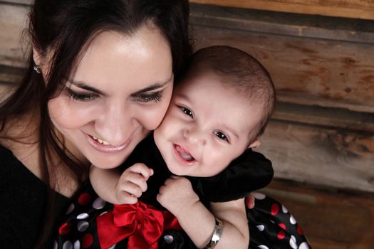 Brunette mother and baby smiling against wooden background