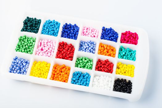 Various colors beads on the white plastic box close up