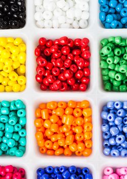 Various colors beads on the white plastic box close up