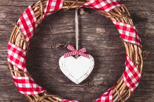 White heart and wreath over wooden old background