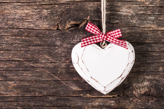 White carved heart over old wooden background, valentine decor