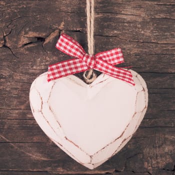 White carved heart over old wooden background, valentine decor