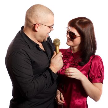 smiling couple singing into a microphone on a white background
