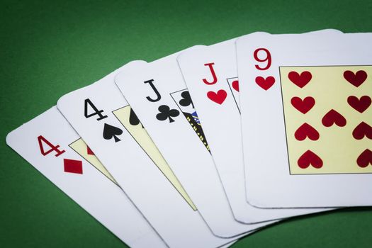 Poker hand call two pairs, consisting of two pairs of cards of the number four, two pairs of cards of j and a letter from the nine of hearts green background