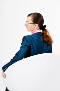 Young woman with glasses and a suit sitting in a chair with his back