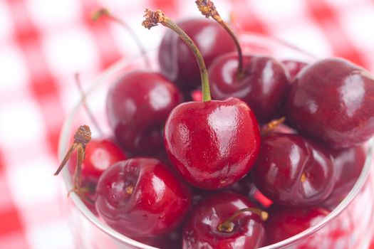 Cherries in a glass bowl on checkered fabric