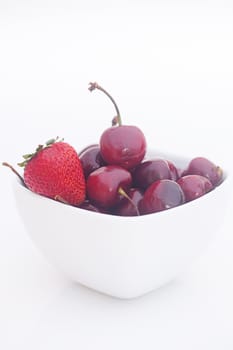 Cherries and strawberry in a ceramic bowl isolated on white