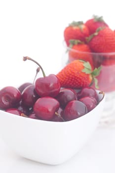 Cherries and strawberry in a ceramic and glass bowl isolated on white