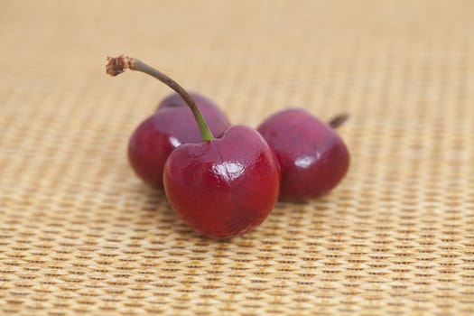 three cherries on wicker mat
