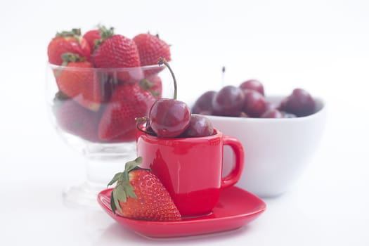 Cherries and strawberry in a ceramic and glass bowl isolated on white