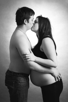 loving happy couple, pregnant woman with her husband, husband kissing woman, black and white