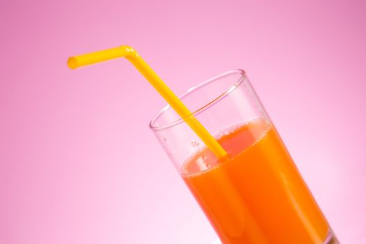 Glass of fresh orange juice with yellow straw, selective focus on glass 