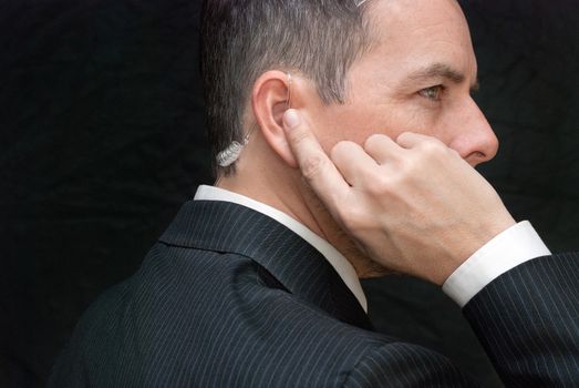 Close-up of a secret service agent listening to his earpiece, side.