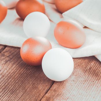 Beige and white chicken eggs on textile tablecloth over rustic wooden table